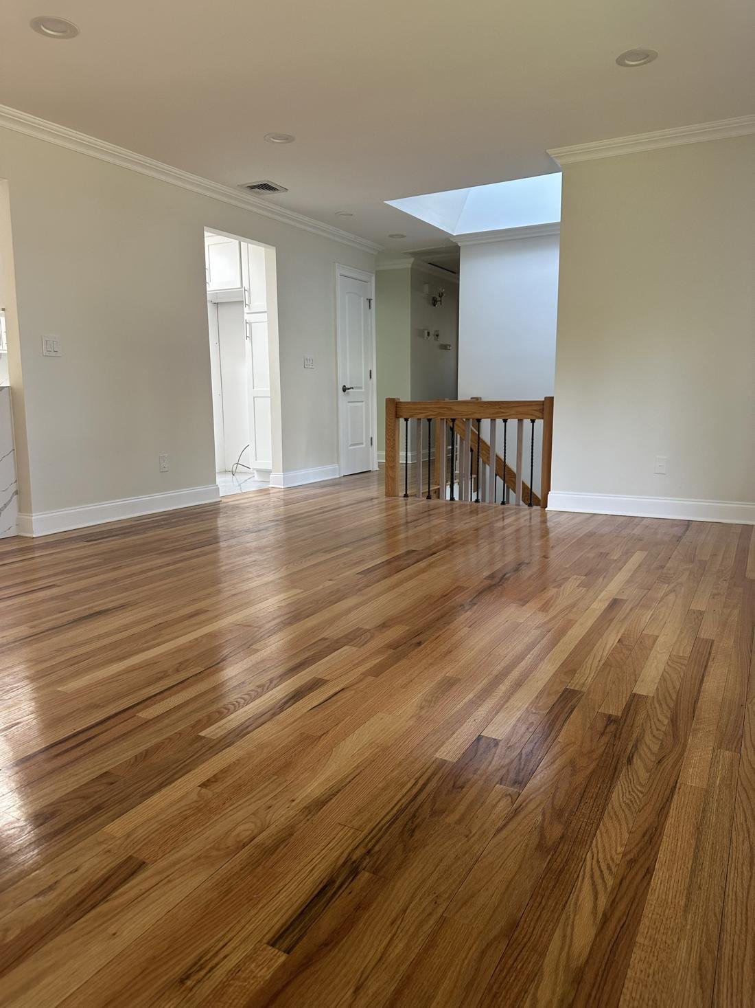 Refinished red oak floor with a gloss finish in an open living area beside a stair rail